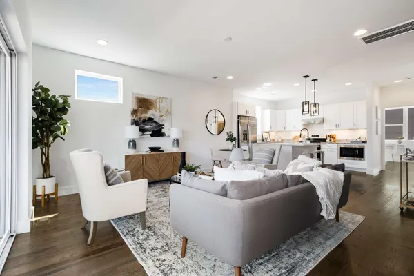 a living room with furniture kitchen view and a chandelier