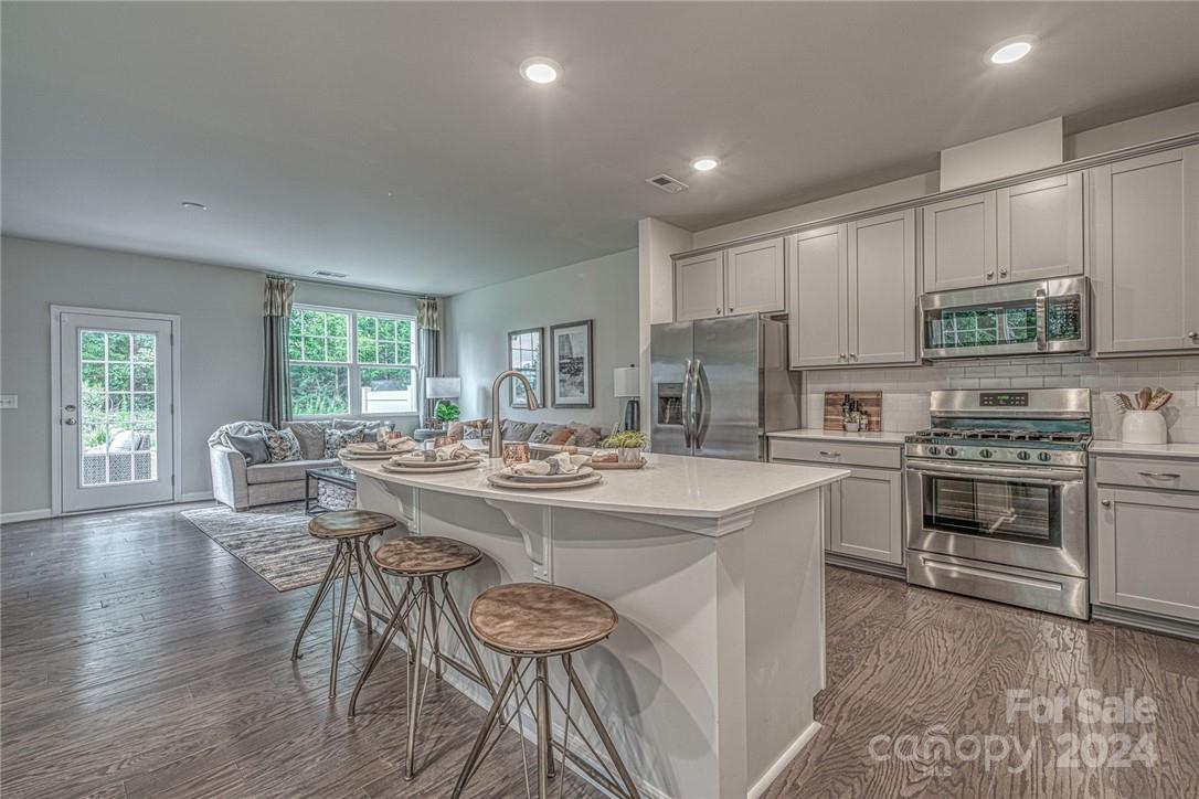 6051 Chelsea Oaks Ridge, Unit 2071 Tega Cay, SC 29708 - Photo 4 of 12 a kitchen with kitchen island a stove a table and chairs in it