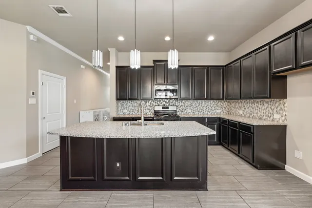 a kitchen with kitchen island granite countertop a sink counter top space stainless steel appliances and cabinets