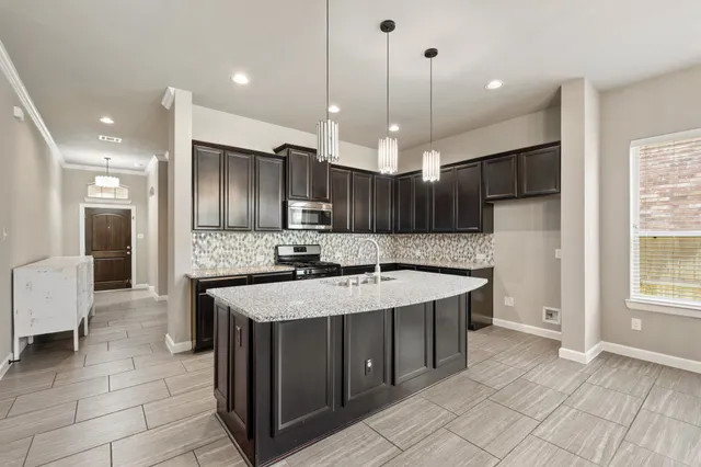a large kitchen with a counter space a sink appliances and cabinets
