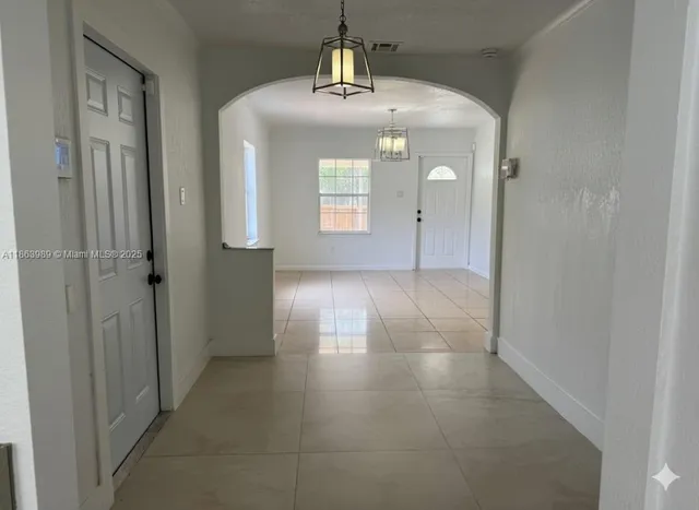a view of a hallway with wooden floor and a chandelier