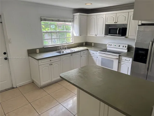 a kitchen with granite countertop a stove a sink and a microwave