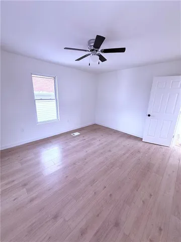 a view of an empty room with a window and wooden floor