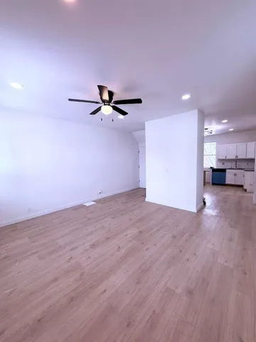 a view of a room with a wooden floor and a ceiling fan