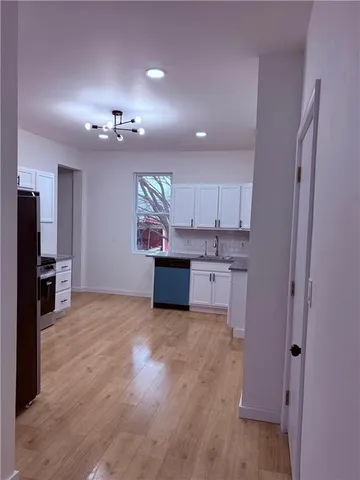 a view of a kitchen with a sink wooden cabinets and a window
