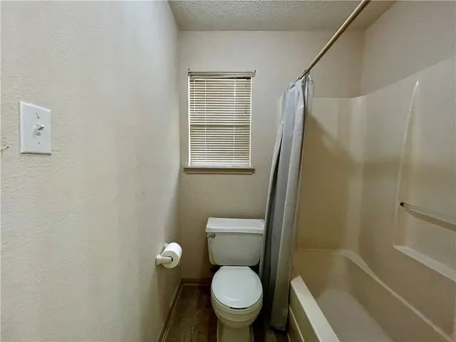 a white toilet sitting next to a bath tub and a shower