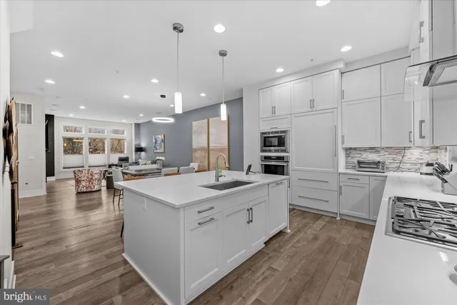 a kitchen with stainless steel appliances granite countertop a stove a sink dishwasher a dining table and chairs with wooden floor