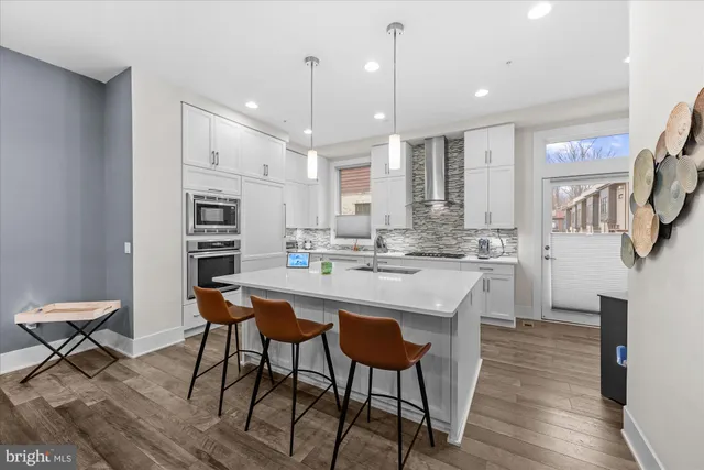a large white kitchen with lots of counter space and stainless steel appliances