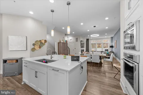 a kitchen with stainless steel appliances kitchen island granite countertop a table chairs and a refrigerator