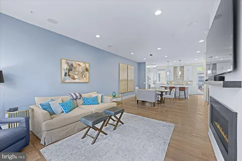 a living room with stainless steel appliances furniture refrigerator and a table