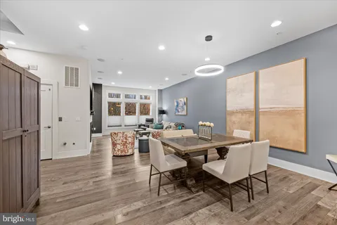 a large white kitchen with a stove a sink dishwasher and a dining table with wooden floor