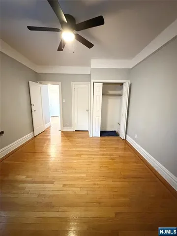 a view of empty room with wooden floor and fan