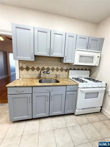 a kitchen with granite countertop a sink and white cabinets