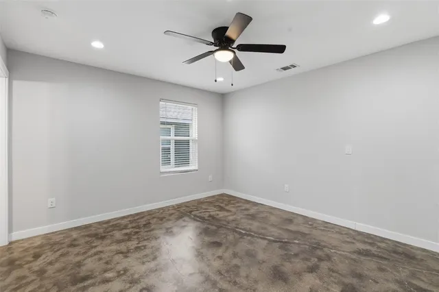an empty room with a ceiling fan and window