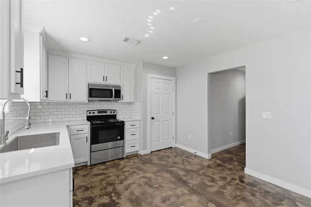a kitchen with white cabinets and appliances