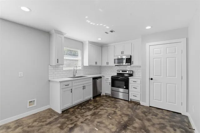 a kitchen with granite countertop white cabinets and stainless steel appliances