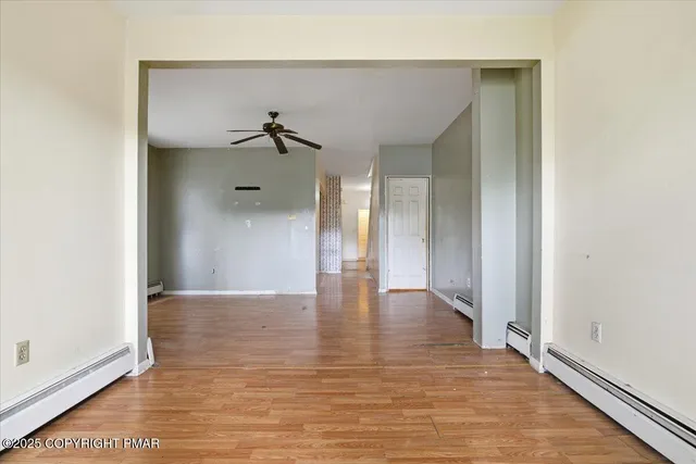 a view of an empty room with wooden floor and a bathroom