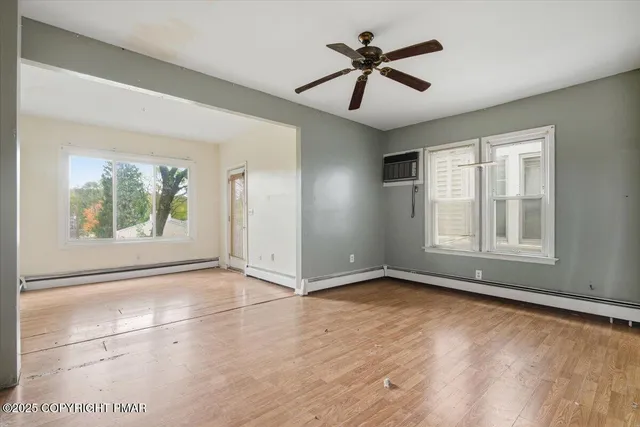 a view of an empty room with a window and wooden floor