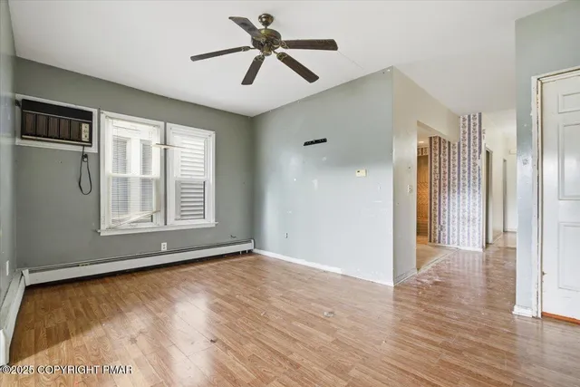 a view of empty room with wooden floor and fan
