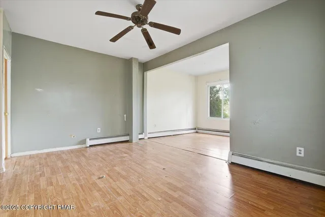 an empty room with wooden floor and windows