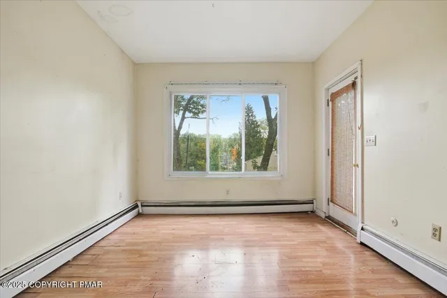 an empty room with wooden floor and windows