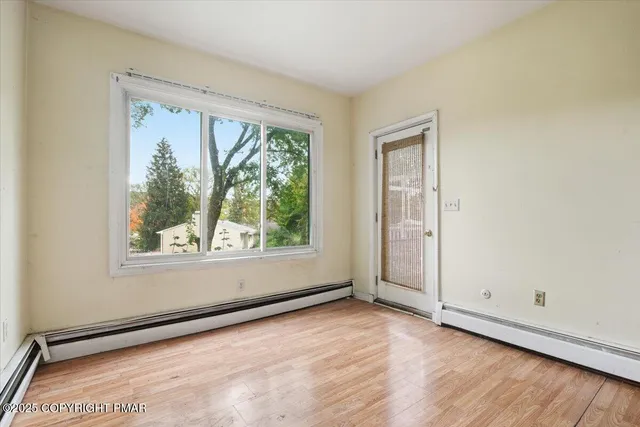 an empty room with wooden floor and windows