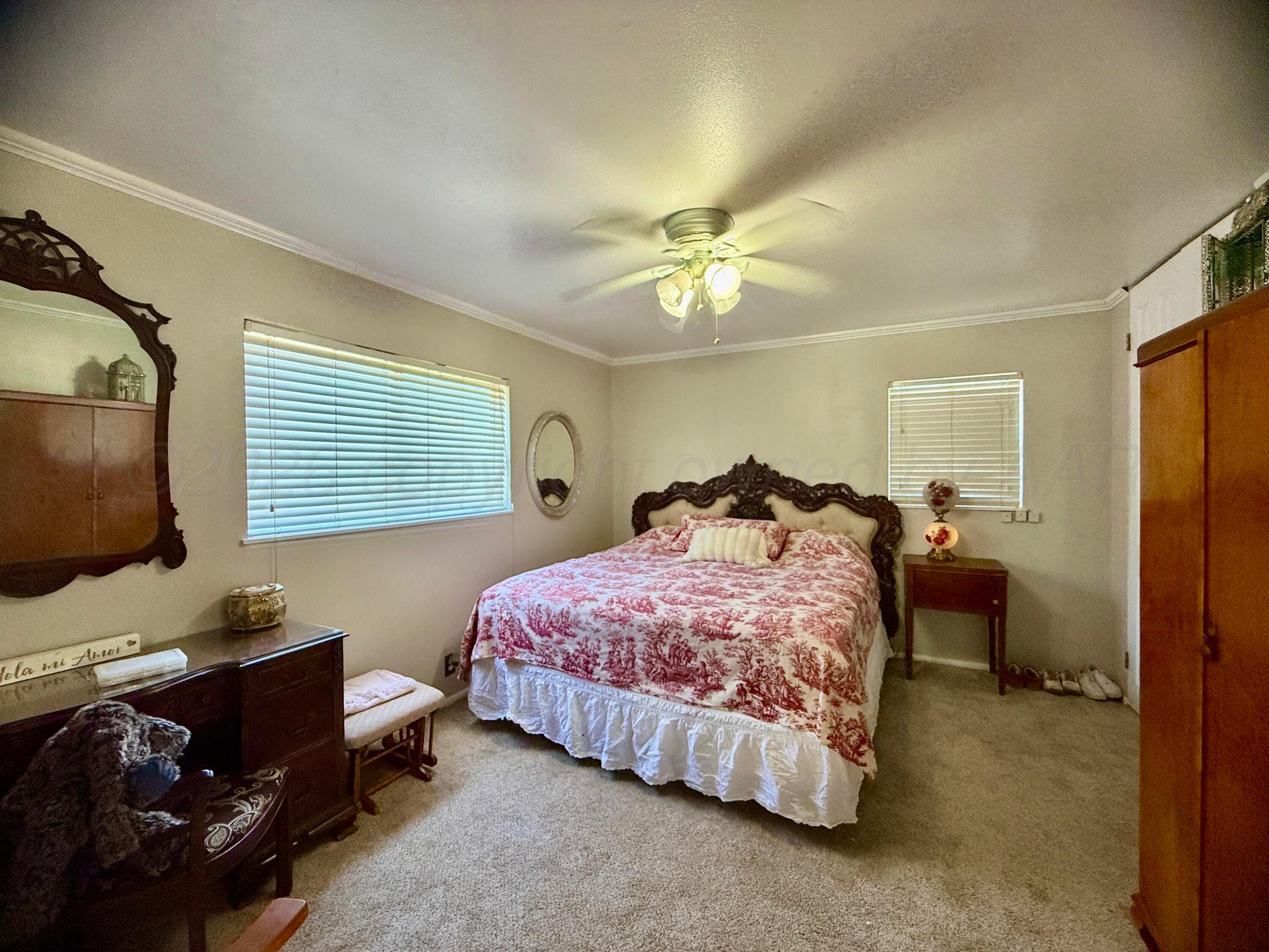 219 Inverness Street Borger, TX 79007 - Photo 20 of 35 a spacious bedroom with a bed and a chandelier