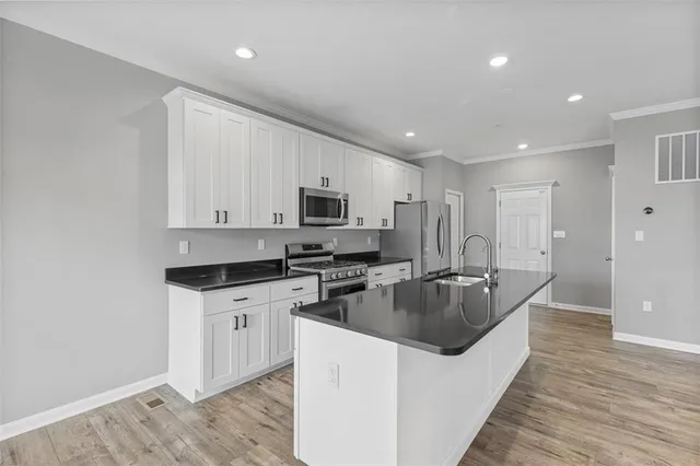 a kitchen with stainless steel appliances granite countertop a sink stove refrigerator and cabinets