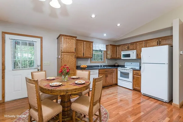 a kitchen with stainless steel appliances granite countertop a refrigerator a stove a sink a dining table and chairs