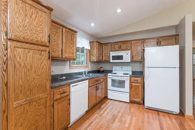 a kitchen with stainless steel appliances granite countertop a refrigerator a stove top oven a sink and dishwasher with wooden floor