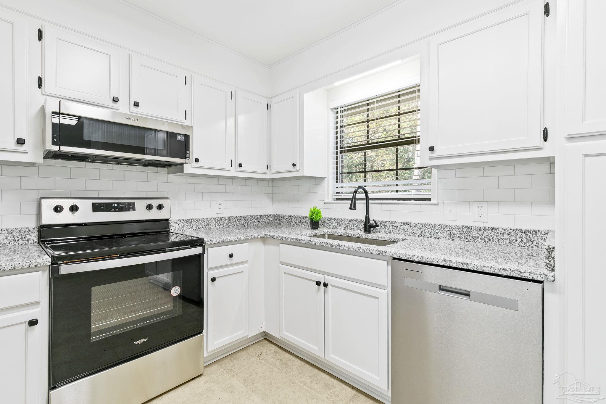 4200 Rigby Road Century, FL 32535 - Photo 4 of 71 a kitchen with stainless steel appliances granite countertop white cabinets a sink and a window