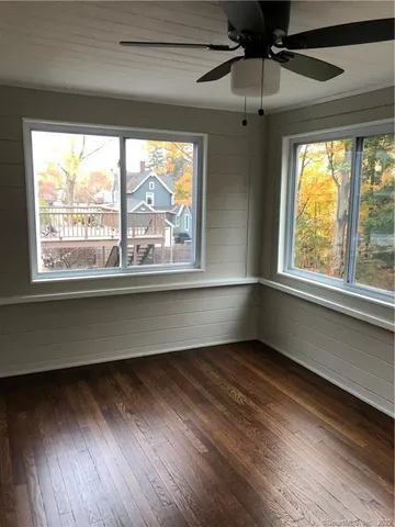 an empty room with wooden floor fireplace and windows