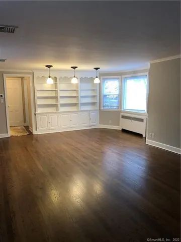 an empty room with wooden floor and window