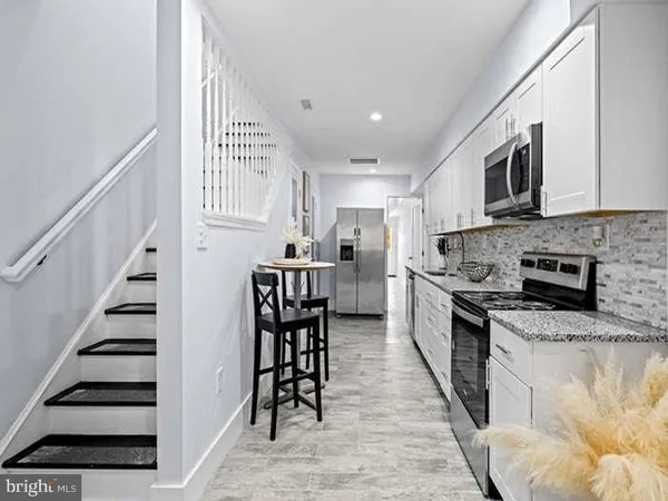 a kitchen with stainless steel appliances granite countertop a stove top oven a sink and a refrigerator