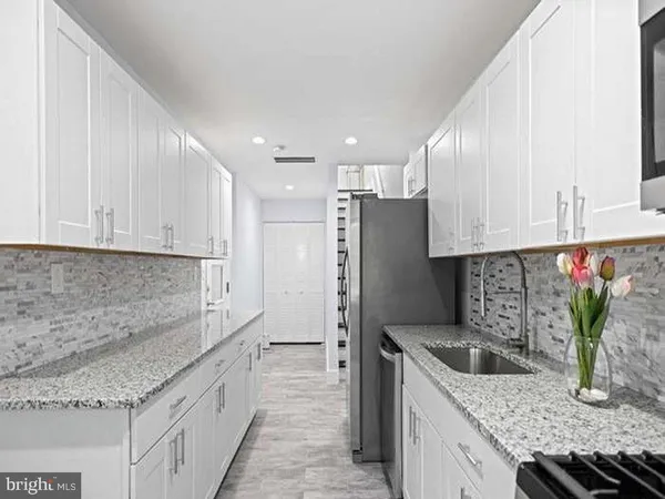 a kitchen with granite countertop a sink stainless steel appliances and white cabinets
