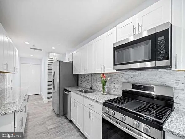 a kitchen with stainless steel appliances kitchen island granite countertop a stove a microwave a sink and cabinets