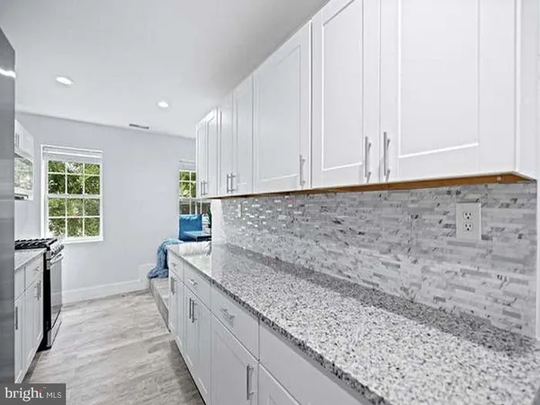 a view of kitchen with granite countertop white cabinets and sink