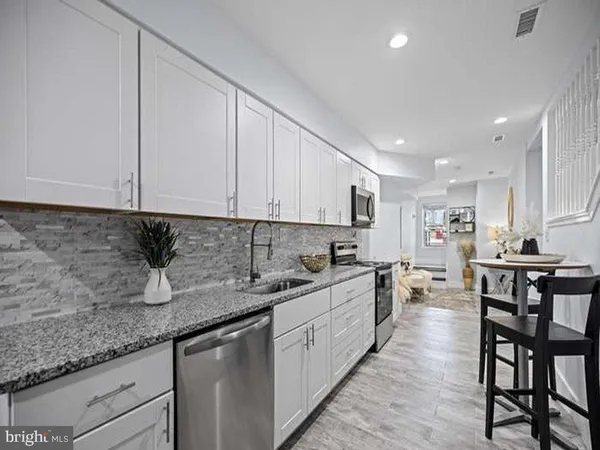 a kitchen with stainless steel appliances granite countertop a sink a stove a dining table and chairs