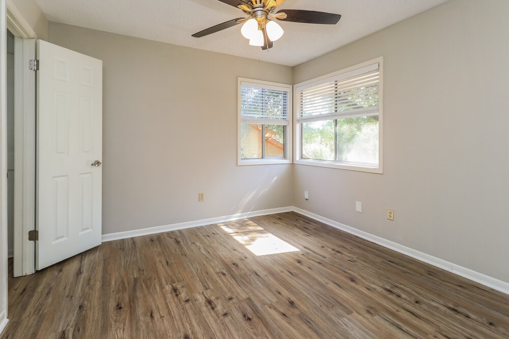 7811 Goldengrove Drive Spring, TX 77379 - Photo 15 of 17 an empty room with wooden floor chandelier fan and windows