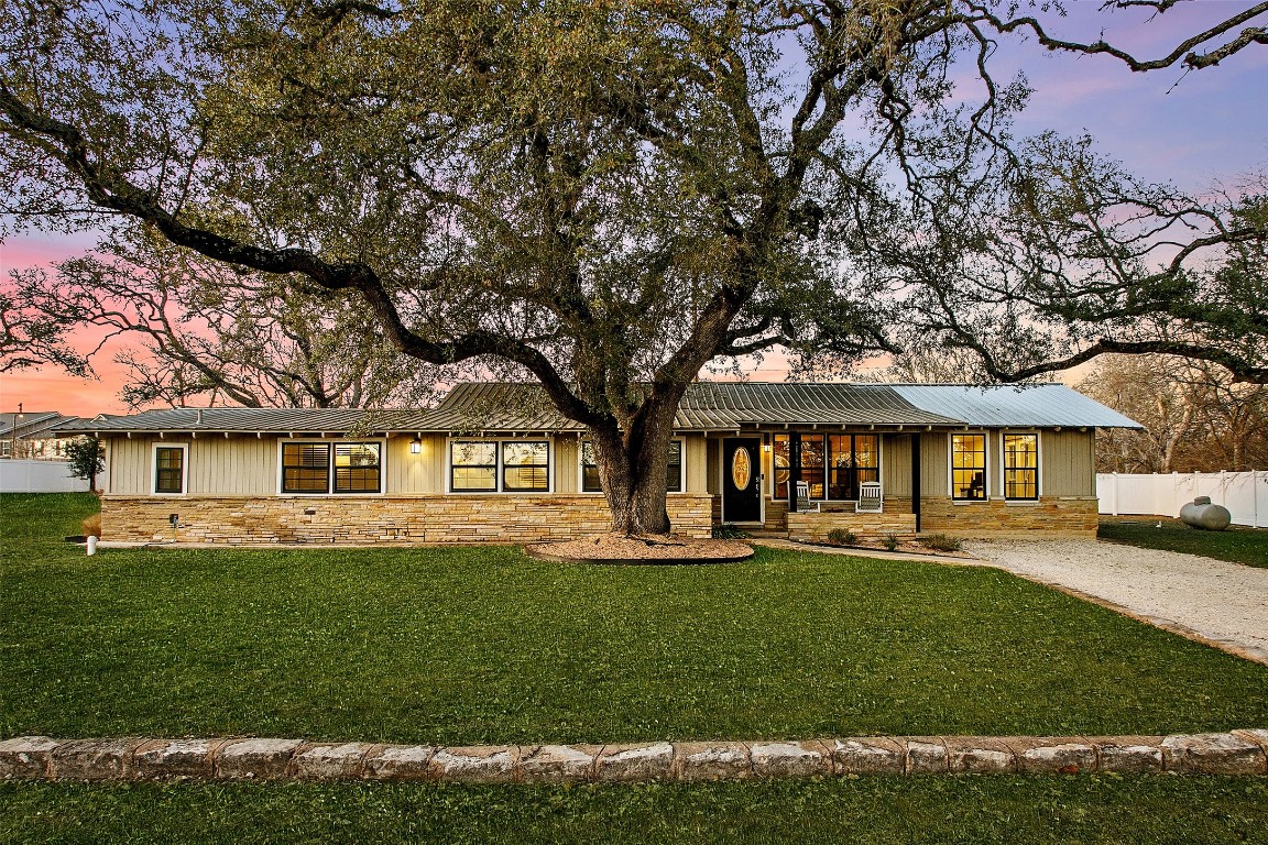Digitally enhanced grass on a single story home featuring stone siding and a porch