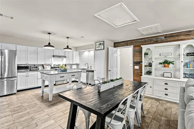 a kitchen with stainless steel appliances kitchen island granite countertop a table chairs sink and cabinets