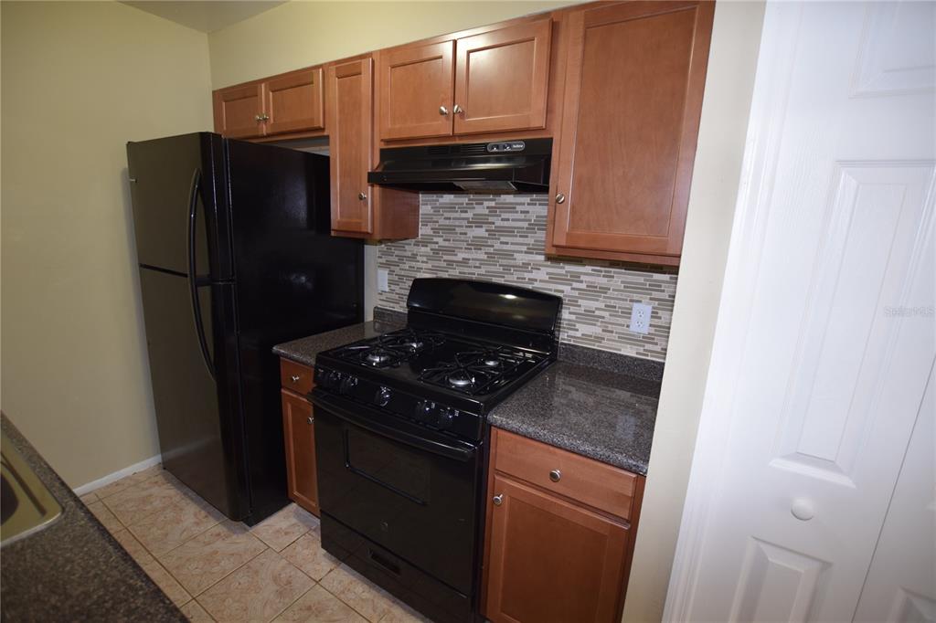 3173 Split Willow Drive Orlando, FL 32808 - Photo 8 of 16 a kitchen with granite countertop a stove and a refrigerator