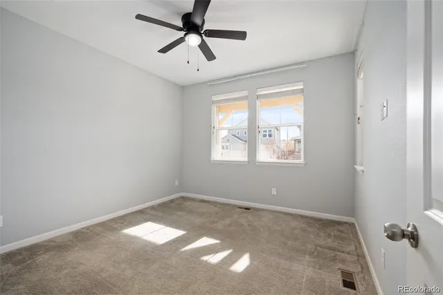 an empty room with windows and fan