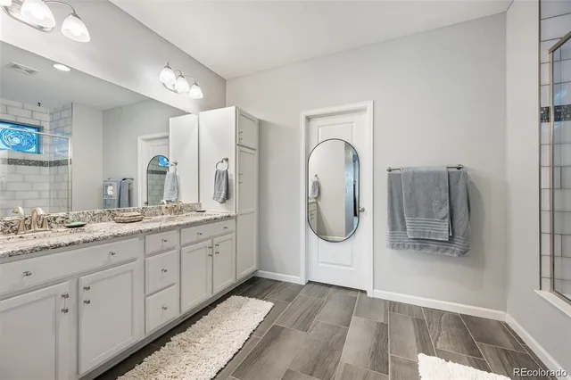 a bathroom with a granite countertop double vanity sink and mirror