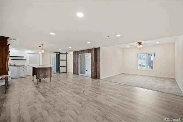 a view of an empty room with kitchen and a window