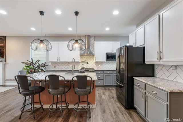 a kitchen with granite countertop a refrigerator a stove a sink and chairs