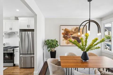 a kitchen with stainless steel appliances granite countertop a refrigerator a sink a stove and white cabinets with wooden floor