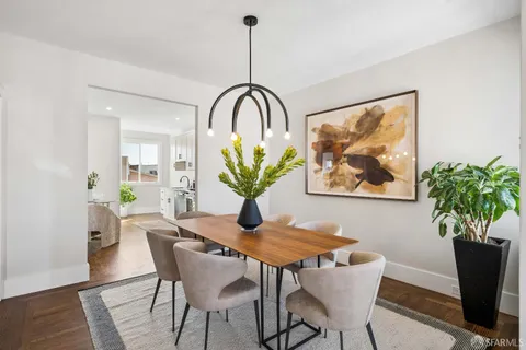 a kitchen with stainless steel appliances a dining table a potted plant and a wooden floor