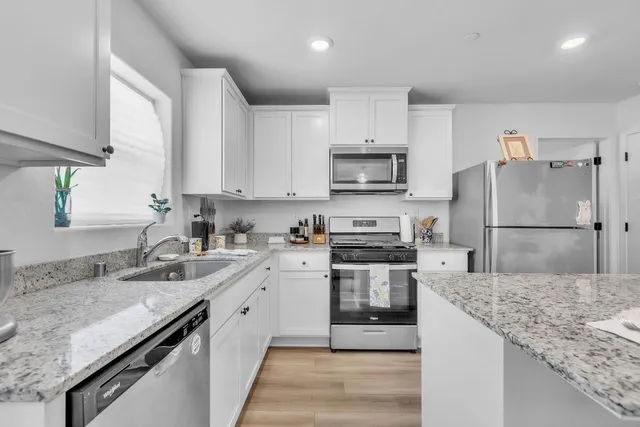 a kitchen with stainless steel appliances granite countertop a sink stove microwave and refrigerator