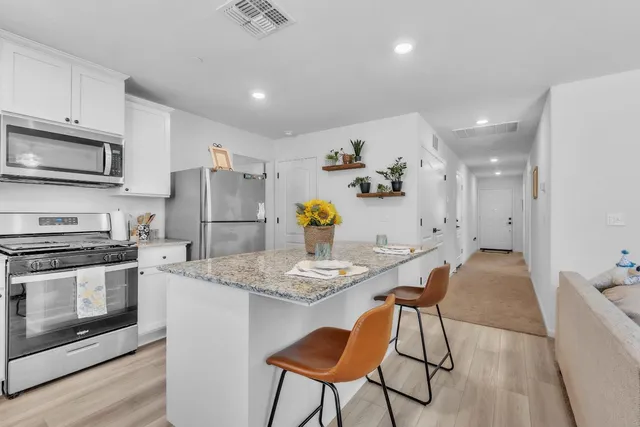 a kitchen with stainless steel appliances granite countertop a stove a refrigerator a microwave a sink and white cabinets